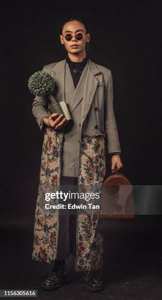 an asian chinese male carrying a plant and a brief case looking at camera with full body length with sunglasses - asian fashion model stock pictures, royalty-free photos & images