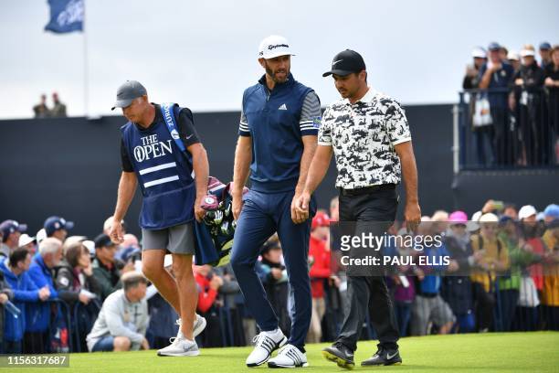 Golfer Dustin Johnson and Australia's Jason Day walk up the fairway from the first hole during the first round of the British Open golf Championships...