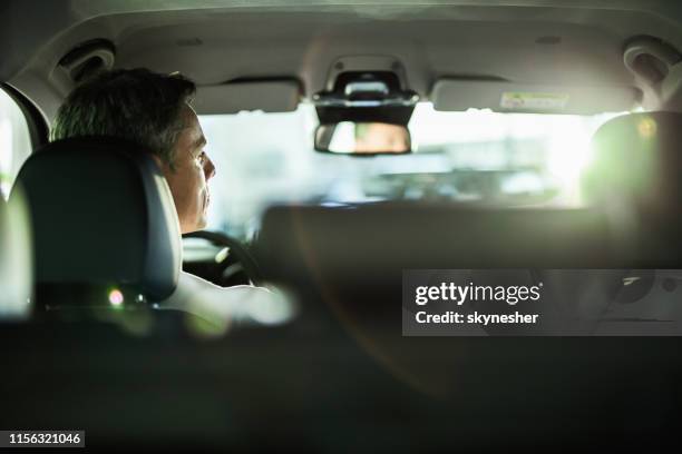 back view of a mid adult man driving a car. - driver seat stock pictures, royalty-free photos & images