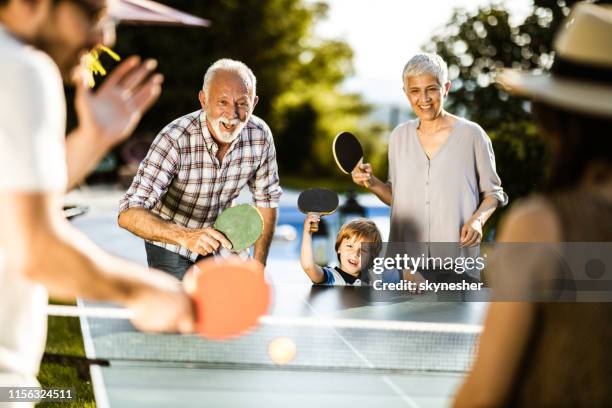 gelukkig uitgebreid gezin met plezier tijdens het spelen van tafeltennis in de achtertuin. - backyard games stockfoto's en -beelden