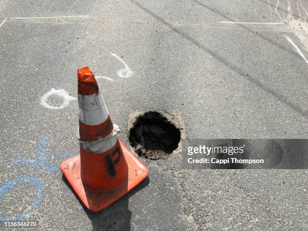 pot hole in roadway creating a hazard to motorists - pothole stockfoto's en -beelden