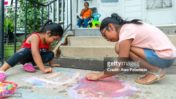 zwei kleine latino mexikanisch-amerikanische mädchen, schwestern, zeichnung mit kreide auf der veranda seines hauses in pennsylvania - hot mexican girls stock-fotos und bilder