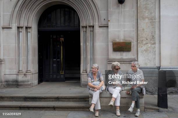 Three elderly ladies rest outside parliamentary offices on Whitehall, on 15th July 2019, in London, England.