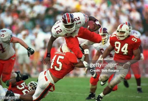 Virginia Tech QB Maurice DeShazo in action vs Miami Twan Russell and Dwayne Johnson at Miami Orange Bowl. Deshazo jumping over Russell. Miami, FL...