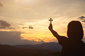 Hand of a girl holding a cross at sunrise, Eucharist Therapy Bless God Helping Repent Catholic Easter Lent Mind Pray. Prayer to God Christian Religion concept background.
