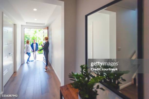 immobilienmakler zeigt einem jungen paar ein neues haus. - immobilienbegehung stock-fotos und bilder