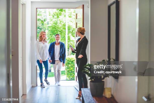 real estate agent showing a young couple a new house. - contrato de arrendamento imagens e fotografias de stock