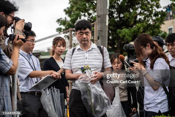 Man is surrounded by members of the media as he lays flowers near the Kyoto Animation Co studio building following an arson attack on July 19, 2019...