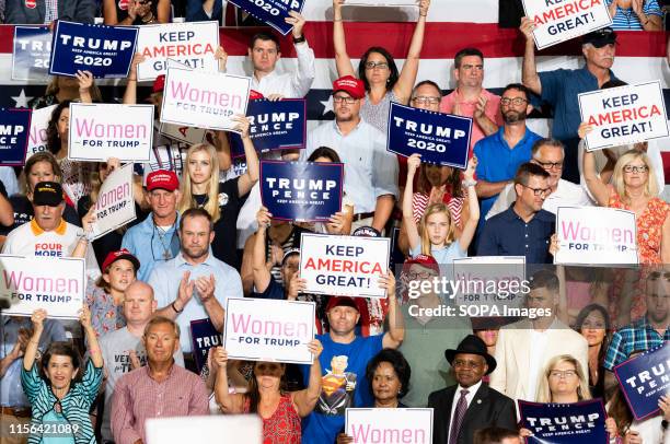 Audience members hold placards during the President Donald Trump's Make America Great Again Rally at the Williams Arena in East Carolina University,...