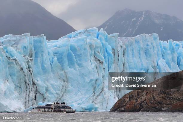 Tourist boat approaches the face of the Perito Moreno glacier, a part of the Southern Patagonian Ice Field, where it feeds into Lago Argentina on...