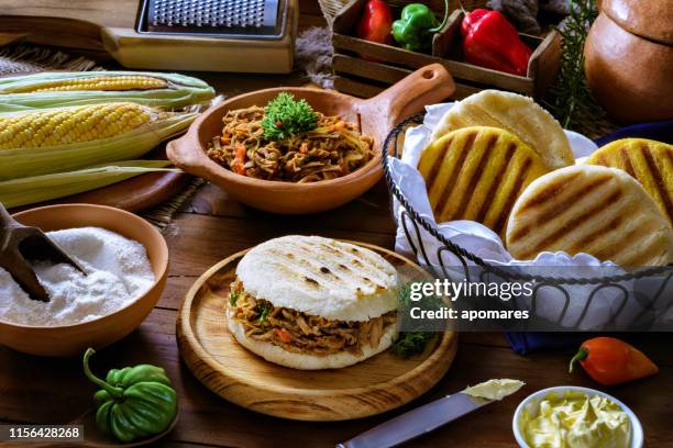 venezolaanse traditionele gerechten, arepa met geraspt vlees. ingrediënten op een tafel in een rustieke keuken. - arepas stockfoto's en -beelden