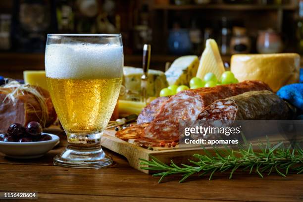 tapas aus käse, schinken, salami, bier und chorizo auf einem rustikalen holztisch - bierwurst stock-fotos und bilder