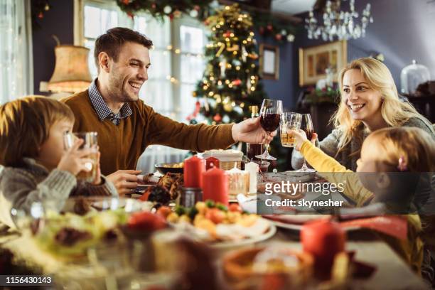 junge glückliche familie toasting während des neujahrsessens am esstisch. - new year new you 2019 stock-fotos und bilder