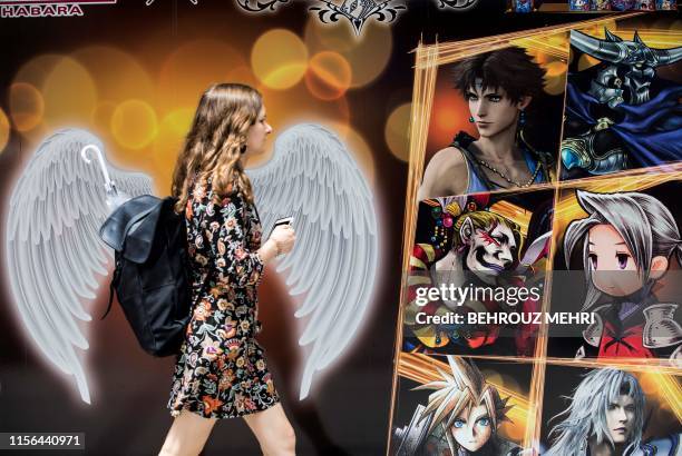 Woman walks past images of characters from digital card games in the Akihabara district in Tokyo on July 19, 2019. - The devastating apparent arson...