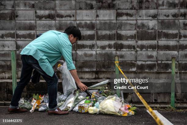 Man lays flowers near the Kyoto Animation Co studio building after an arson attack, on July 19, 2019 in Kyoto, Japan. Thirty three people are...