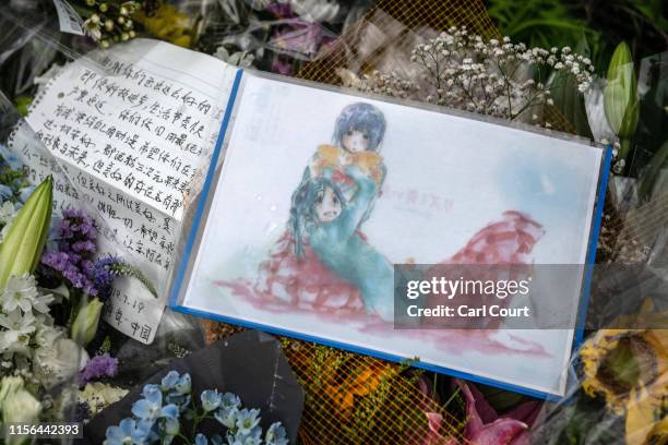 An anime cartoon drawing is laid amongst flowers and tributes near the Kyoto Animation Co studio building after an arson attack, on July 19, 2019 in...