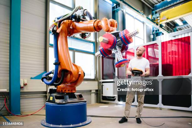 industrie 4.0: junger ingenieur arbeitet an einem roboterarm - roboter stock-fotos und bilder