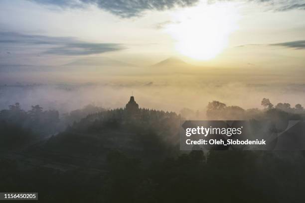 scenic aerial view of borobudur temple at sunrise in fog - theravada stock pictures, royalty-free photos & images