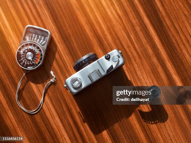 rangefinder film camera with a photographic film and light meter on a wooden table from high angle view - light meter stock pictures, royalty-free photos & images