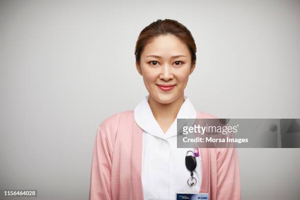 portrait of female nurse against white background - nurse and portrait and white background and smiling and female and looking at camera stock-fotos und bilder