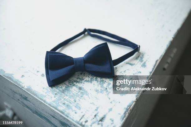 blue bow tie, a fashion accessory for a man, groom or businessman, on an old shabby, peeling wooden table, close-up. preparing the groom for the wedding day. blurred background - papillon accessorio da portare al collo foto e immagini stock
