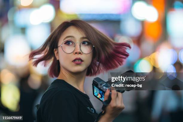 mujer joven sosteniendo la cámara por la noche - fotografar fotografías e imágenes de stock