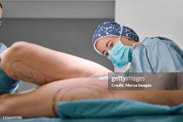 confident female plastic surgeon operating patient - microchirurgie stockfoto's en -beelden