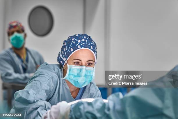 healthcare workers performing plastic surgery - microchirurgie stockfoto's en -beelden