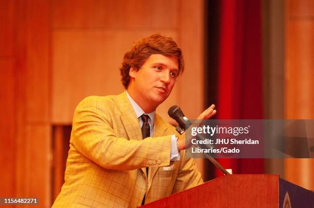 Three-quarter profile view of political commentator Tucker Carlson, speaking from a podium during a Milton S Eisenhower Symposium at the Johns...