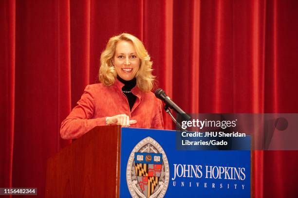 Writer and former Central Intelligence Agent Valerie Plame, standing behind a podium and smiling, during a Milton S Eisenhower Symposium at the Johns...