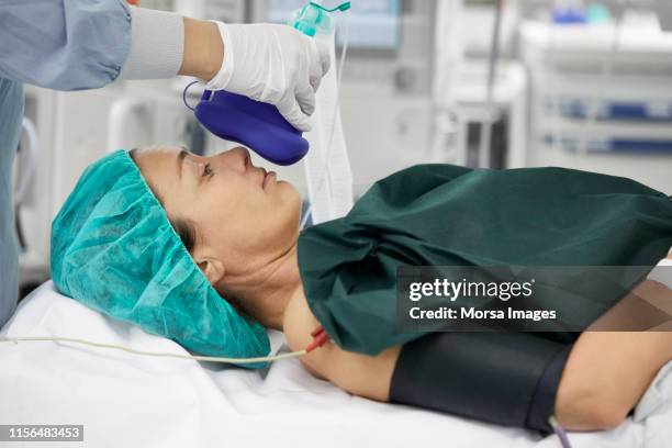 female doctor holding oxygen mask for patient - operationstisch stock-fotos und bilder