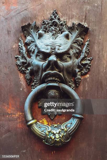 door knocker with demon face in rome - door knocker stock-fotos und bilder