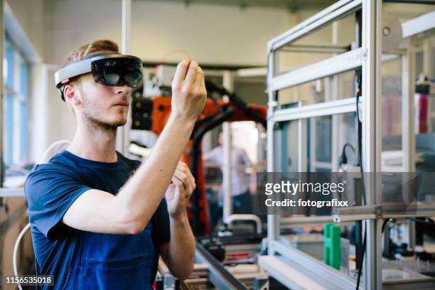 industry 4.0: young engineer works with a head-mounted display - industry 4 0 imagens e fotografias de stock