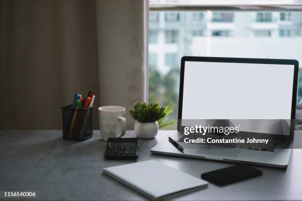 laptop with blank white screen and office supply items on word desk - notepad table stockfoto's en -beelden