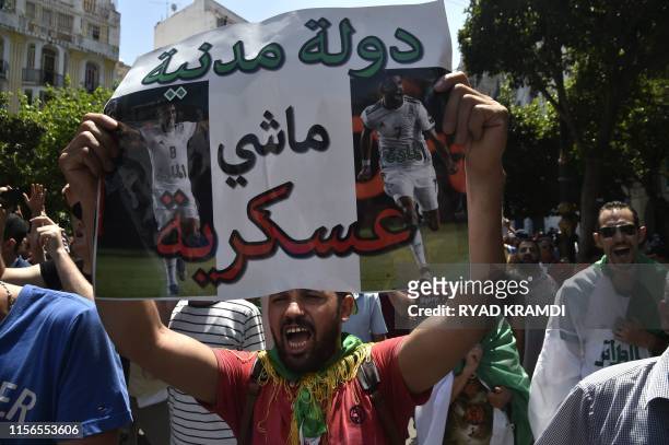 Algerian demonstrators, brandishing a placard with pictures of their football team's players, protest in the streets of the capital Algiers against...