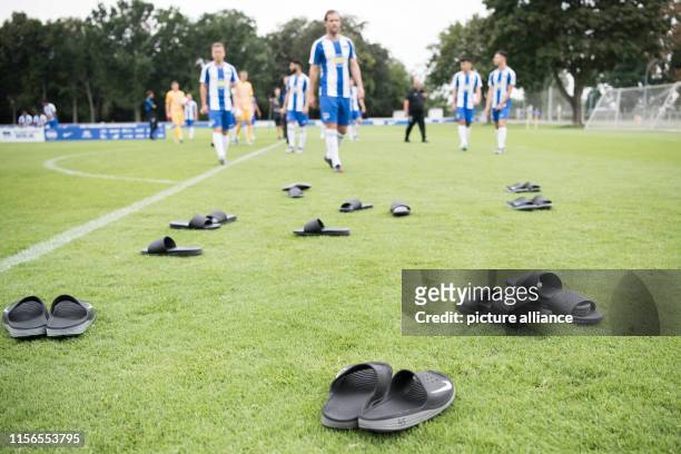 Numerous slippers of the U23 players are lying on the grass in front of the team photo of the Bundesliga team of Hertha BSC. Photo: Jörg...
