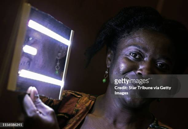 Employee Oredola Taylor held one of the 100 LED lights assembled by 3M employees as part of the 3Mgives-Team Africa and New Vision program, during...