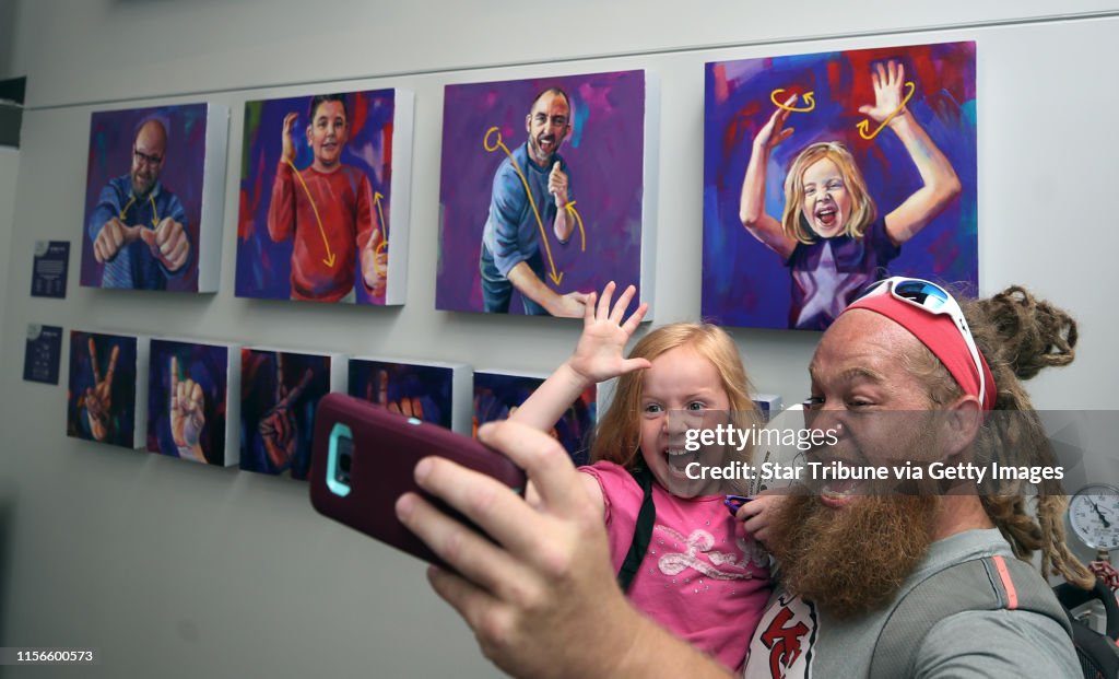 Teddie Barnett took a photo with is daughter Lana Barnett 6; Lana is a student at the Metro Deaf School. Students from the school posed for pictures as they used American Sign Language to communicate. Artist Leslie Barlow painted the outline of each photo