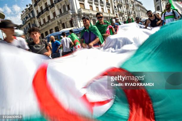 Algerian demonstrators wave a large national flag as they gather in the streets of the capital Algiers against the ruling class amid an ongoing...