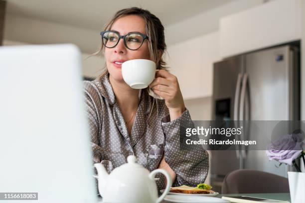 woman drinking coffee while checking laptop - colombia business breakfast meeting stock pictures, royalty-free photos & images