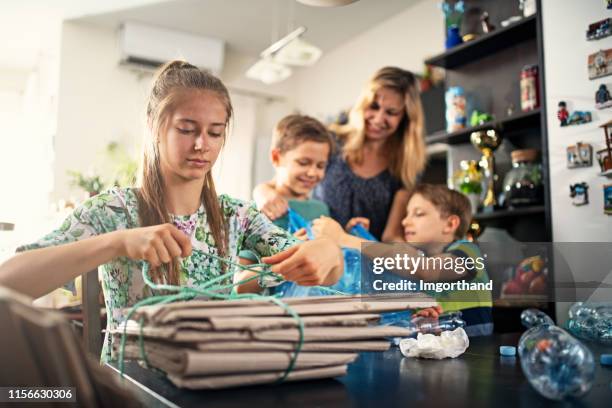 family segregating plastic bottles, cans, glass bottles and cardboard. - family separation stock pictures, royalty-free photos & images