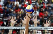 Volleyball player spike with hands blocking over the net