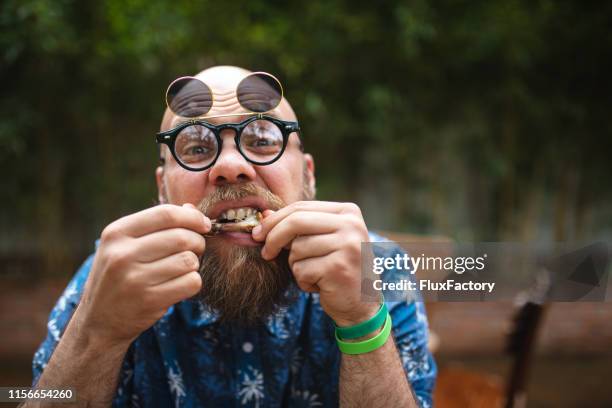 hipster mann kaut auf einem hühnerflügel knochen - eating chicken stock-fotos und bilder