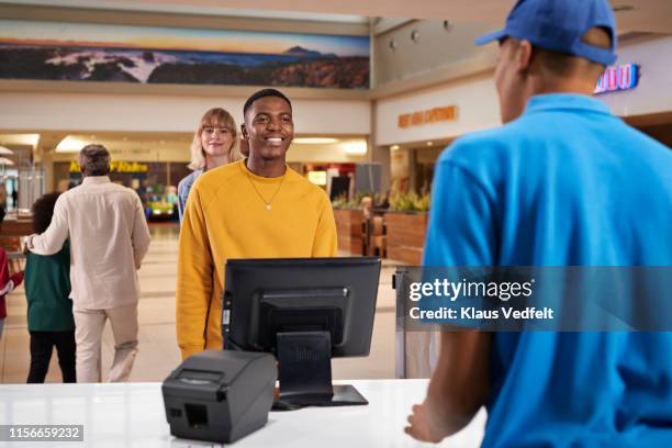 smiling man buying tickets at movie theater - counter stand stock-fotos und bilder