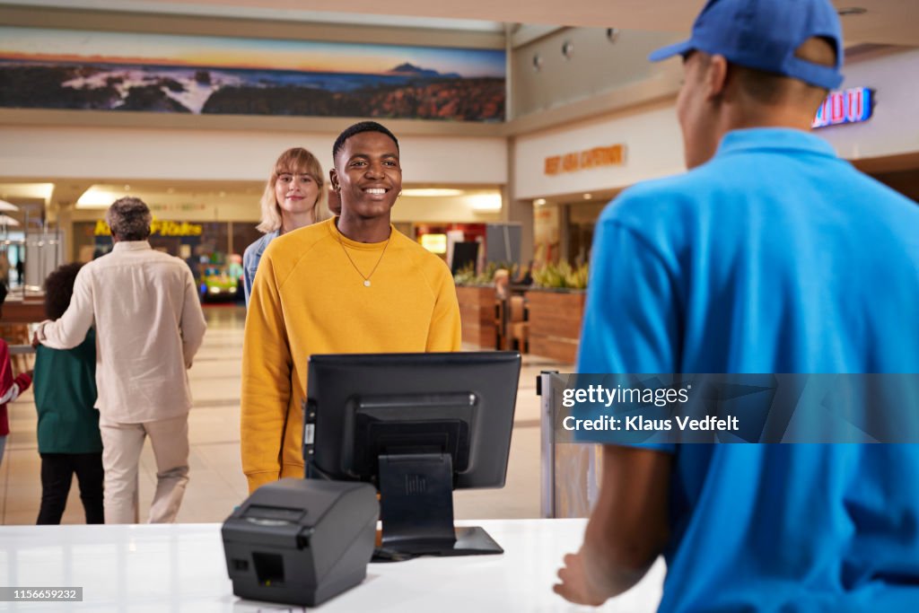 Smiling man buying tickets at movie theater