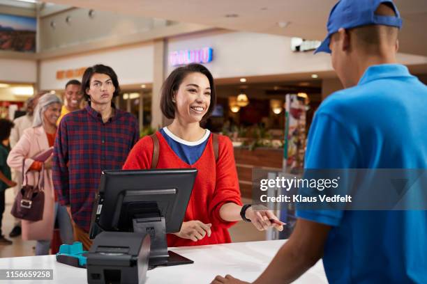 smiling woman paying for movie tickets - vendor payment stock pictures, royalty-free photos & images