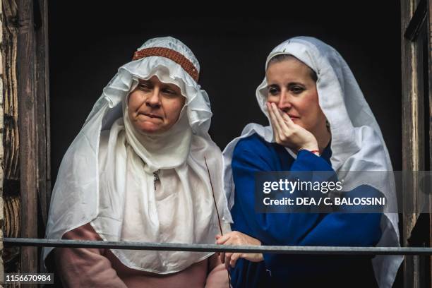 Women with veils looking out the window, Pallavicino Castle, Varano de' Melegari, Parma, Italy, 13th century. Historical reenactment.
