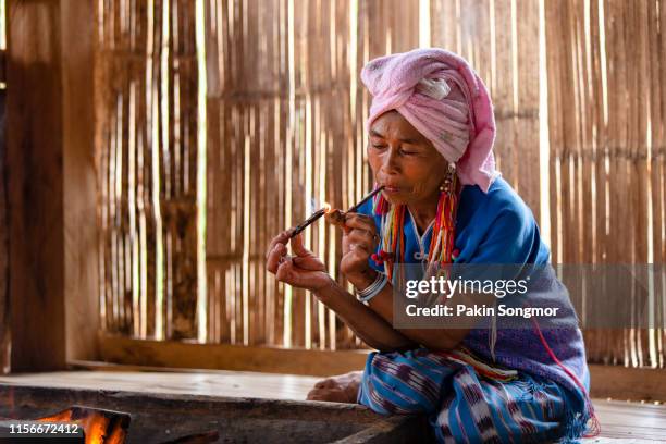 karen hill tribe is smoking tobacco pipe with traditional clothes in local village at hill area in chiang mai - hill tribes stock pictures, royalty-free photos & images