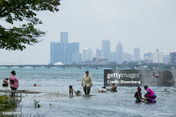 People stand in the water at a beach on Belle Isle in Detroit, Michigan, U.S., on Friday, July 19, 2019. The forecast for this weekend shows the heat...