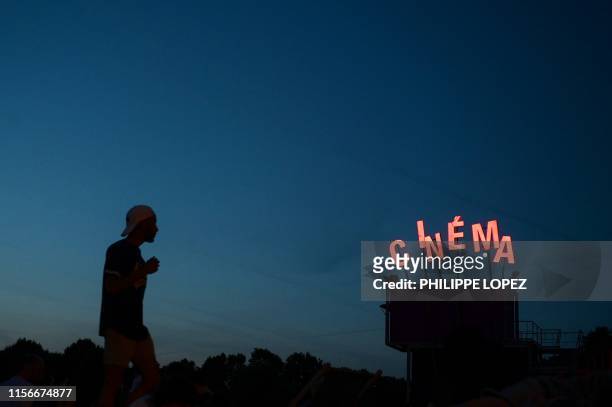 Man looks for a spot to sit at an outdoor movie screening at the park of la Villette in Paris on July 19, 2019.